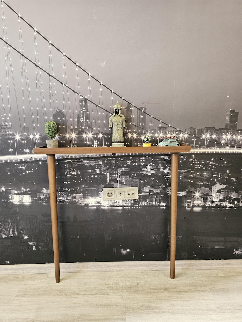 This minimalist wooden console adds warmth and natural beauty to any hallway, living room, or entryway. Each piece is handcrafted from solid beech wood, sanded and stained by hand to achieve a smooth, durable walnut finish.