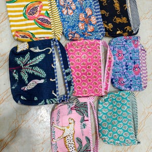 May include: A collection of colorful, patterned pouches. Designs include papaya slices on yellow stripes, blue floral, black tigers, navy birds, pink floral, purple floral, pink cheetah, and teal floral. Each pouch has a matching handle and striped trim.
