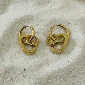 May include: A pair of gold-toned hoop earrings, each featuring a circular hoop connected to a larger, elongated oval link. The earrings have a polished, metallic finish and are displayed side-by-side, showcasing their interlocking design.
