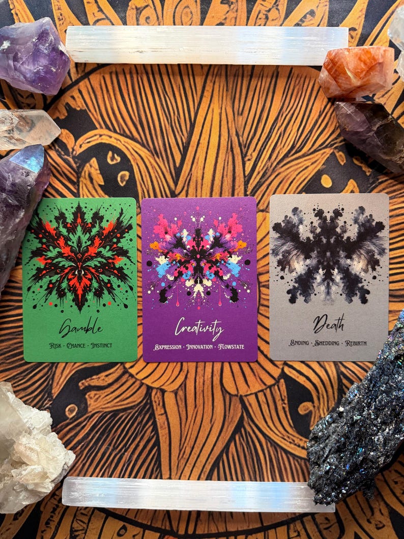 Pu&ograve; includere: Tre carte dei tarocchi con disegni simmetrici e testo. Le carte sono etichettate "Gamble", "Creativity" e "Death". La carta Gamble &egrave; verde con accenti rossi e neri. La carta Creativity &egrave; viola con schizzi di vernice colorati. La carta Death &egrave; grigia con inchiostro nero.