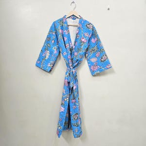 May include: A blue floral patterned robe with a tie closure, hanging on a wooden hanger. The robe features a quilted design with pink and green floral accents. The robe is made of a lightweight fabric.