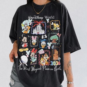 May include: Black t-shirt featuring a colorful graphic of Disney characters and landmarks. The design includes Mickey Mouse, Minnie Mouse, Donald Duck, and Chip and Dale, with the text "Walt Disney World" and "The Most Magical Place on Earth". The year "2026" is also displayed.