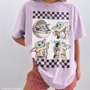 Puede incluir: Una camiseta de color lila claro con un dise&ntilde;o de Grogu de The Mandalorian en cuatro poses diferentes. El dise&ntilde;o incluye un patr&oacute;n de tablero de ajedrez en blanco y negro. La camiseta es Comfort Colors Orchid. La modelo lleva unos shorts a cuadros rojos y blancos.