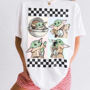 Puede incluir: Camiseta blanca con un dise&ntilde;o de cuatro paneles que muestra ilustraciones de un personaje alien&iacute;gena verde en varias poses. El dise&ntilde;o est&aacute; sobre fondos pastel y enmarcado por un patr&oacute;n de cuadros blanco y negro. El texto "COMFORT COLORS WHITE" est&aacute; impreso en la parte inferior.