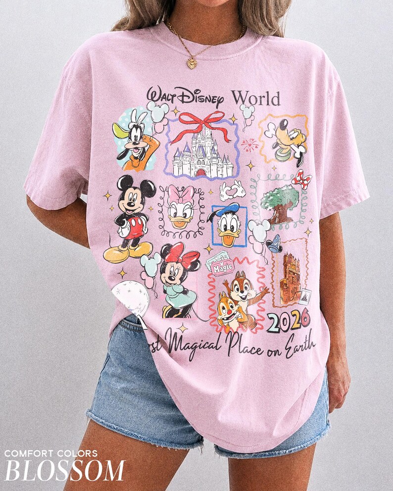 May include: A light pink t-shirt with a graphic featuring various Disney characters and the text "Walt Disney World" and "2026". The shirt also has the text "Most Magical Place on Earth".