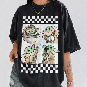 Puede incluir: Camiseta negra con un dise&ntilde;o gr&aacute;fico de cuatro paneles de un personaje alien&iacute;gena verde en varias poses. El dise&ntilde;o est&aacute; enmarcado por un patr&oacute;n de cuadros blancos y negros. Las palabras "COMFORT COLORS" y "BLACK" est&aacute;n impresas en la parte inferior.