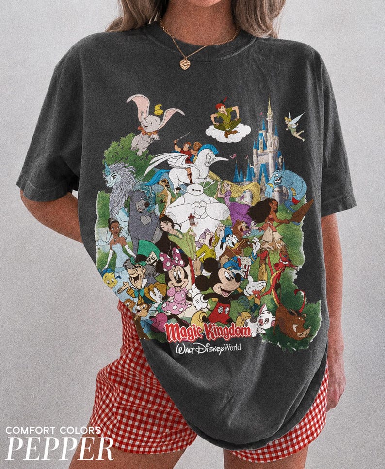 Peut inclure: T-shirt gris fonc&eacute; avec un imprim&eacute; color&eacute; de personnages Disney, dont Mickey et Dumbo. Le texte "Magic Kingdom Walt Disney World" est imprim&eacute;. Fait partie de la collection Comfort Colors Pepper.