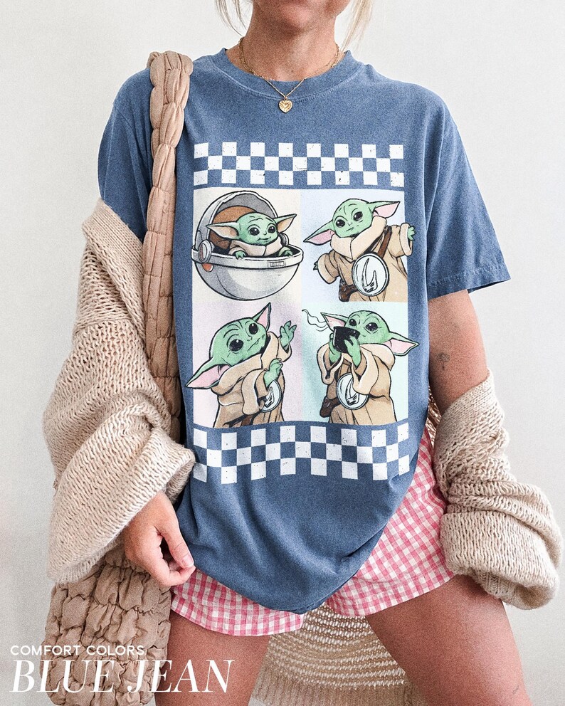 Puede incluir: Camiseta azul vaquero con un gr&aacute;fico de un personaje de una popular serie de ciencia ficci&oacute;n. El gr&aacute;fico incluye cuatro im&aacute;genes del personaje, sobre un fondo a cuadros. El texto "COMFORT COLORS BLUE JEAN" est&aacute; en la parte inferior.