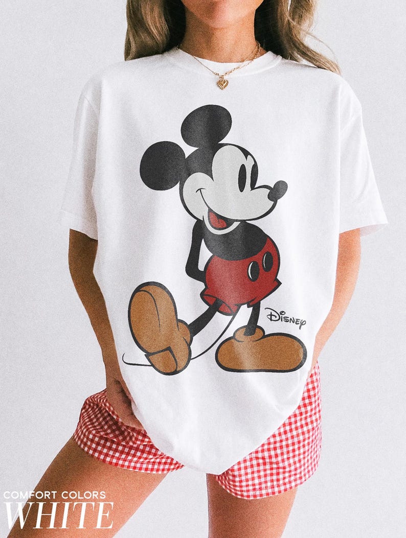 K&ouml;nnte beinhalten: Wei&szlig;es T-Shirt mit einer Mickey Mouse-Grafik in Schwarz, Rot und Braun. Das Disney-Logo ist auf dem T-Shirt aufgedruckt. Der Text "COMFORT COLORS WHITE" ist unten im Bild aufgedruckt.