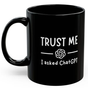May include: Black ceramic mug with white text reading "TRUST ME", a graphic, and "I asked ChatGPT". The mug features a curved handle and a glossy finish. Ideal for tea or coffee.