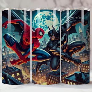May include: Three stainless steel tumblers with a dynamic illustration of Spider-Man and Batman set against a cityscape. The design depicts the superheroes in action, with a full moon and city buildings in the background. The tumblers are suitable for cold drinks.