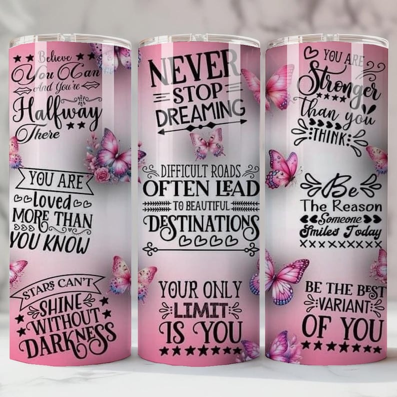 May include: Three pink insulated tumblers with inspirational quotes and butterfly designs. The tumblers feature phrases like "Believe You Can" and "Never Stop Dreaming." Each tumbler is approximately 20 cm tall.