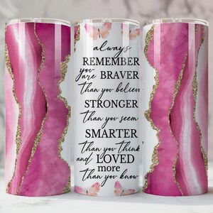 May include: A stainless steel tumbler with a pink and white agate design and gold glitter accents. The tumbler features the text "always REMEMBER you are BRAVER Than you believe, STRONGER Than you seem, SMARTER Than you think and LOVED more Than you know."