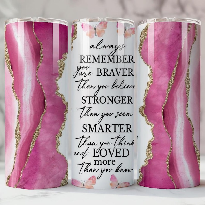 May include: A stainless steel tumbler with a pink and white agate design and gold glitter accents. The tumbler features the text "always REMEMBER you are BRAVER Than you believe, STRONGER Than you seem, SMARTER Than you think and LOVED more Than you know."