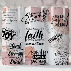 May include: Three stainless steel tumblers with floral designs and inspirational quotes. The tumblers feature text such as "Choose Joy," "She is Strong," and "Trusting God." The background has a soft pink and white colour scheme.