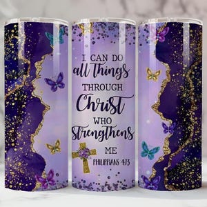 May include: A purple and gold tumbler with a design featuring butterflies and the text "I CAN DO all THINGS THROUGH CHRIST who STRENGTHENS ME Philippians 4:13." The tumbler has a gold and purple abstract design.