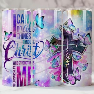 May include: Three stainless steel tumblers with a wraparound design. The design features colourful butterflies, flowers, and a cross with the word "Faith". The text "I can do all things through Christ who strengthens me" is also displayed. The background is a watercolour wash of purple, blue, and pink.