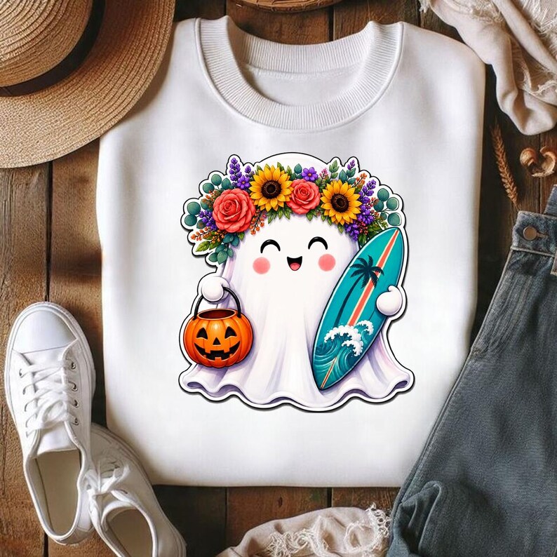 Pode incluir: Uma camisola branca de gola redonda com o gr&aacute;fico de um fantasma sorridente a usar uma coroa de flores coloridas de girass&oacute;is e rosas. O fantasma segura um balde de ab&oacute;bora laranja e uma prancha de surf turquesa com uma palmeira.