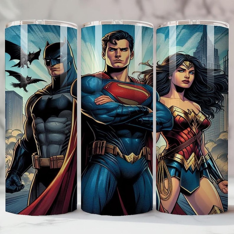 May include: Three stainless steel tumblers featuring DC Comics superheroes Batman, Superman, and Wonder Woman. The tumblers have a blue background with cityscapes and illustrations of the characters in their iconic costumes. The Batman tumbler has bats flying in the background.