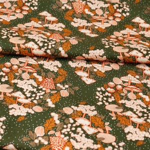 以下が含まれることがあります： キノコ、白いベリー、オレンジ色の葉の繰り返し模様が特徴の濃い緑色の生地。キノコは、オレンジ色の茎に白いと桃色の帽子が付いています。生地はまだら模様です。