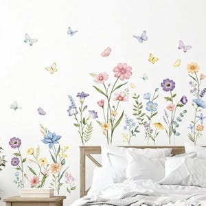 May include: A set of wall decals featuring watercolor illustrations of various wildflowers in shades of pink, blue, yellow, and purple, accompanied by several small butterflies in soft pastel colors, arranged in a scattered floral pattern.
