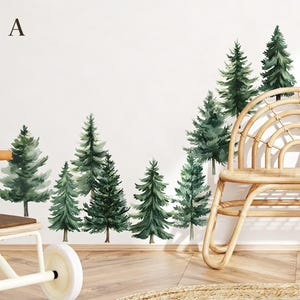 May include: Watercolor wall decals depicting a forest of green pine trees. The trees are arranged in a row against a white wall, creating a nature-inspired design. A wooden chair is in the foreground.