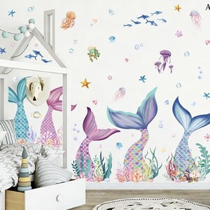 May include: A whimsical wall decal set featuring mermaid tails in shades of purple and blue, surrounded by aquatic elements like jellyfish, starfish, and bubbles. The design creates a dreamy underwater scene, perfect for a child's bedroom or playroom.