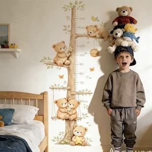 Può includere: Un adesivo da parete raffigurante un albero marrone con foglie verdi e diversi orsacchiotti, tra cui una coppia su un'altalena e uno che tiene una stella gialla. Sul tronco è stampata una scala di misurazione verticale da 50 cm a 150 cm.