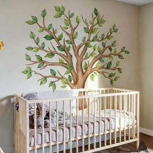 May include: A nursery with a light wood crib and a large wall decal of a tree. The tree decal features a brown trunk and branches with green leaves. The crib is filled with a white sheet and several stuffed animals.