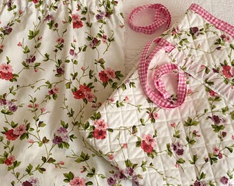 Può includere: Pannello tenda bianco a fantasia floreale e tessuto trapuntato con finiture a quadretti rosa. Il tessuto presenta un motivo ripetuto di fiori rossi e viola con foglie verdi. È incluso anche un nastro a quadretti rosa abbinato.