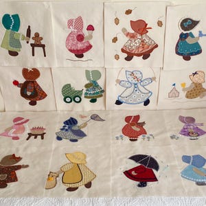 May include: A collection of fifteen square fabric quilt blocks featuring appliqué designs of figures in bonnets performing various activities, including baking, playing with toys, gardening, and walking in the rain, all set against a cream background.