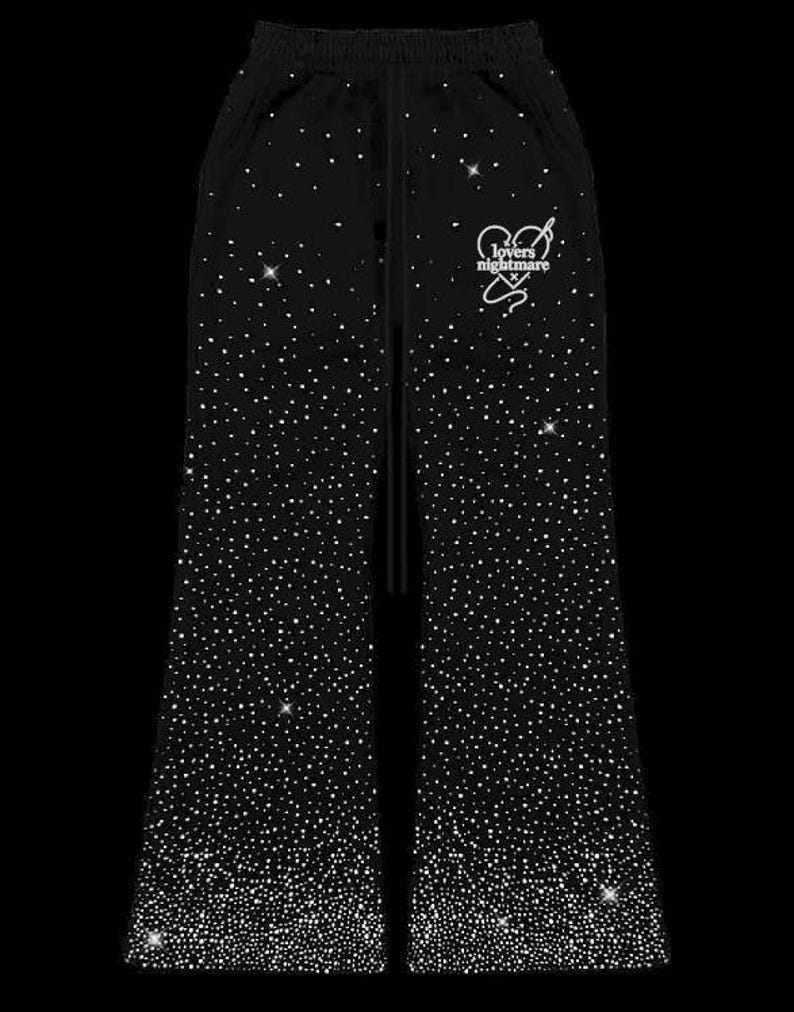 K&ouml;nnte beinhalten: Schwarze Jogginghose mit funkelndem Strass-Design. Die Hose hat einen Kordelzug in der Taille und eine wei&szlig;e Grafik mit der Aufschrift "lovers nightmare" mit Herz und Stern.