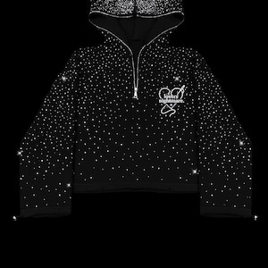 K&ouml;nnte beinhalten: Schwarzer Kapuzenpullover mit halbem Rei&szlig;verschluss, bedeckt mit funkelnden Verzierungen. Der Hoodie zeigt den Text "GOLDIVER" und eine Grafik mit den Worten "lovers nightmare". Das Sweatshirt hat ein verk&uuml;rztes Design.