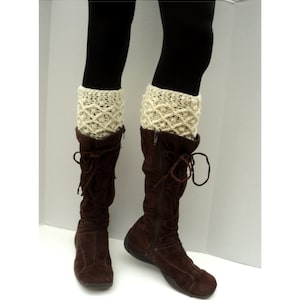 May include: A pair of brown suede boots with laces and a zipper. The boots are worn with cream-colored knitted leg warmers.
