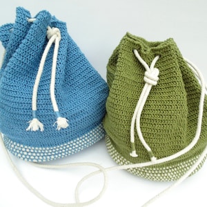 Puede incluir: Dos bolsas de cordón de ganchillo, una azul y otra verde, con cordones y ribetes blancos.