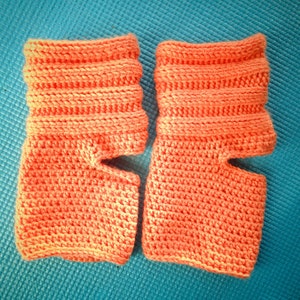 May include: A pair of peach-colored fingerless crochet gloves with a ribbed pattern.