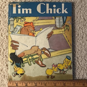 Puede incluir: Libro infantil vintage titulado "Tim Chick" con una portada azul. La ilustración muestra un gallo leyendo un libro, con varios pollitos amarillos jugando cerca. El libro está abierto y el gallo lleva gafas.