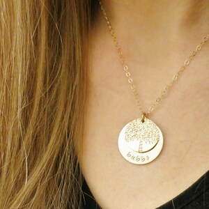 May include: A gold necklace with a round pendant featuring a tree design and the word "bubba" engraved on the bottom.