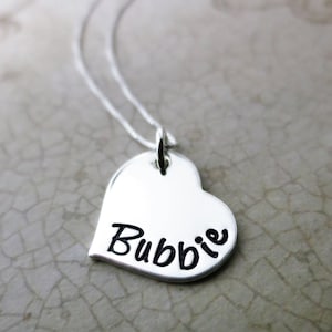 May include: A silver necklace with a heart-shaped pendant that says "Bubbie" on it.