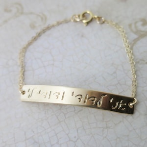 May include: Gold chain bracelet with a flat bar charm engraved with Hebrew text.
