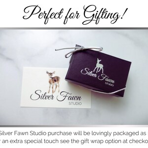 Pu&ograve; includere: Una piccola scatola regalo nera con un logo di cervo bianco che dice "Silver Fawn Studio". La scatola &egrave; legata con un nastro argentato. Un biglietto bianco con lo stesso logo &egrave; accanto alla scatola.
