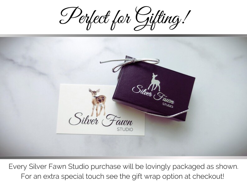 Pu&ograve; includere: Una piccola scatola regalo nera con un logo di cervo bianco che dice "Silver Fawn Studio". La scatola &egrave; legata con un nastro argentato. Un biglietto bianco con lo stesso logo &egrave; accanto alla scatola.