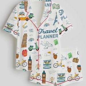 Puede incluir: Conjunto de pijama blanco con tem&aacute;tica de viajes. La camiseta de manga corta y los pantalones cortos presentan un patr&oacute;n repetido de iconos de viaje, incluyendo bicicletas, scooters y monumentos. La parte superior tiene ribetes rojos y la frase "Travel Planner".
