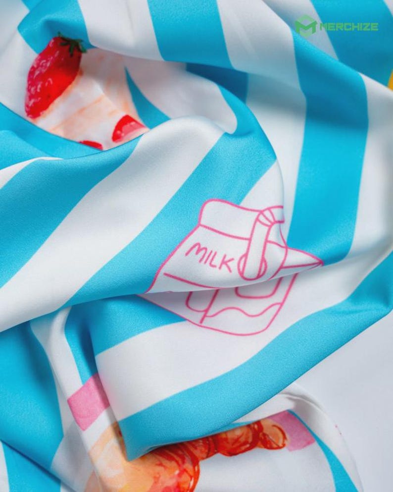 Puede incluir: Pa&ntilde;uelo de seda con un patr&oacute;n repetido de rayas azules y blancas, fresas y una ilustraci&oacute;n de cart&oacute;n de leche. El pa&ntilde;uelo tiene una textura suave y fluida y una paleta de colores vibrantes.