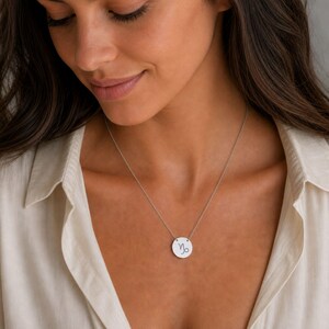 Pu&ograve; includere: Una collana color argento con un ciondolo circolare che presenta il simbolo zodiacale del Capricorno inciso in nero. Il ciondolo pende da una sottile e delicata catenina color argento che poggia sulla clavicola in modo ben visibile.