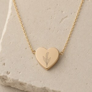 Pu&ograve; includere: Una collana con ciondolo a forma di cuore color oro, caratterizzata da una delicata incisione a linee sottili di un mughetto al centro del cuore. Il ciondolo &egrave; fissato a una sottile catenina color oro abbinata con maglie circolari uniformi.