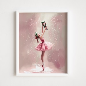 May include: A framed print of a ballerina in a pink tutu, holding a nutcracker. The illustration features a young dancer with a green headband and red accents, set against a soft pink background with falling snow.