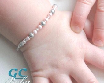 May include: A baby's bracelet featuring a delicate design of pink and silver beads. The bracelet is on a baby's wrist. The image includes the text "GC Baby .etsy.com" in the lower left corner.