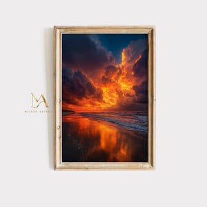 May include: A vertical framed wall art print featuring a dramatic sunset over a beach. The sky is filled with dark blue and vibrant orange clouds, reflecting onto the wet sand and ocean waves. The frame is a light-toned wood with a thin profile.