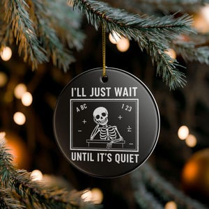 Puede incluir: Adorno navideño redondo negro con el texto "I'LL JUST WAIT UNTIL IT'S QUIET" y un esqueleto. El adorno también presenta las letras "ABC" y los números "123".